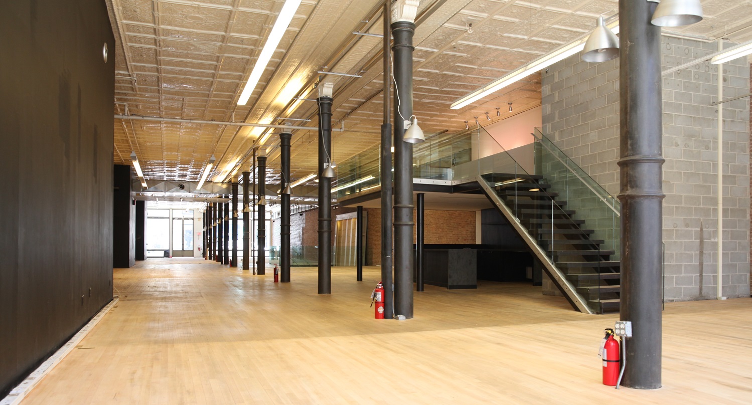 Long open loft floor with a row of iron columns and an open steel stair