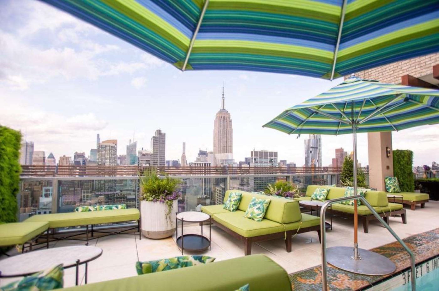 Rooftop terrace with striped umbrellas, green lounges and Empire State Building view