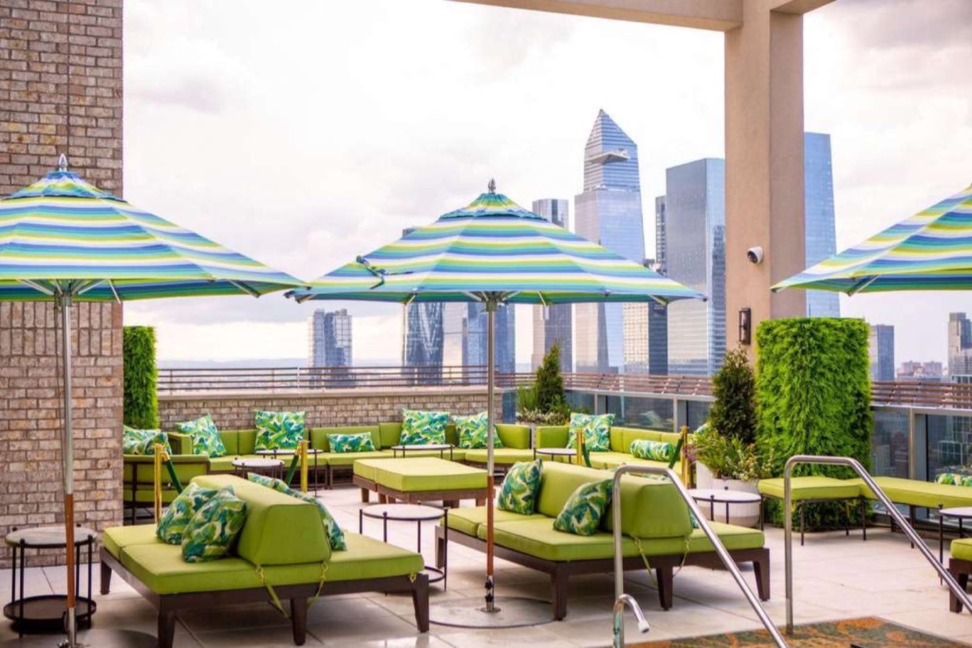 Rooftop lounge seating under umbrellas with Hudson Yards skyline behind