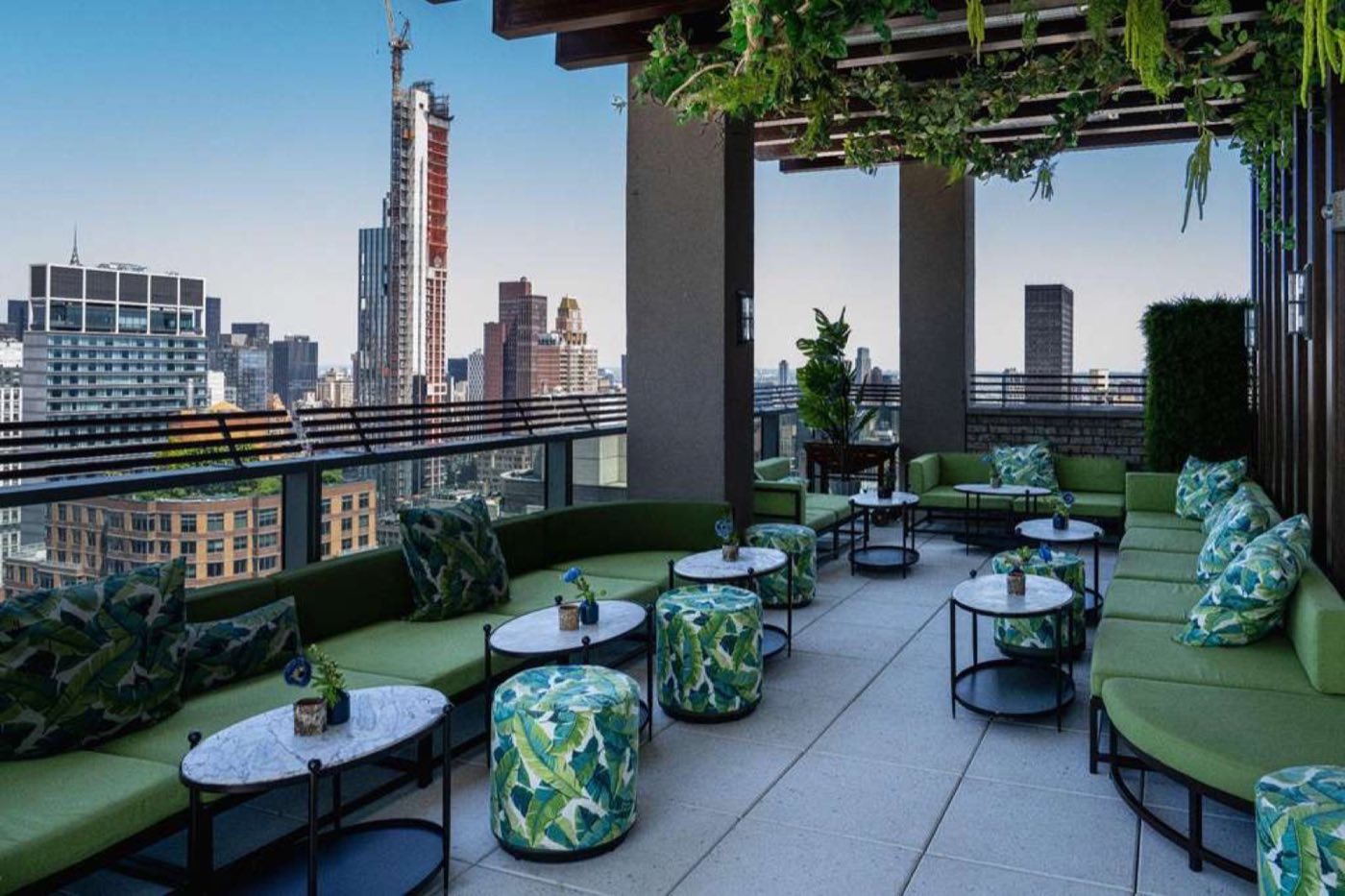 Covered rooftop terrace with banquettes, side tables and city views