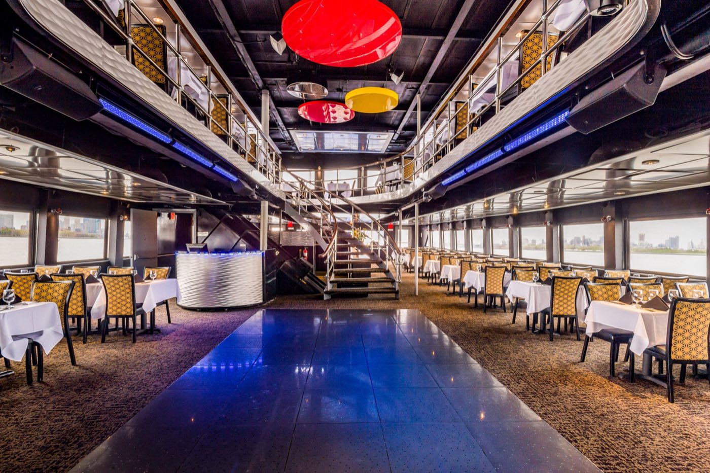 Main dining deck with a dark dance floor, curved staircase and balcony above