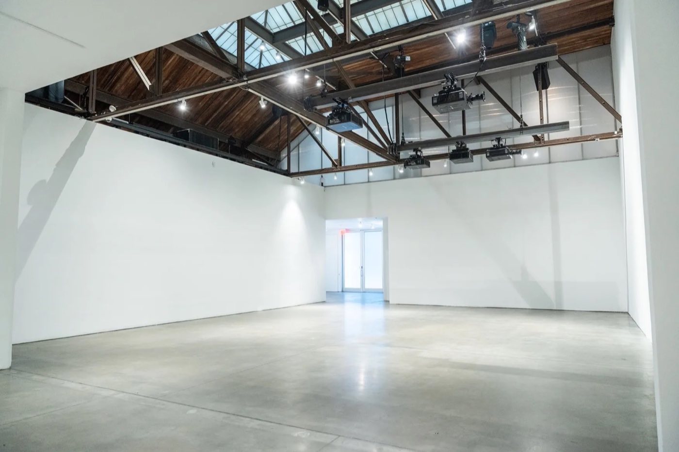 Empty main studio with white walls, concrete floor, exposed timber trusses and skylights