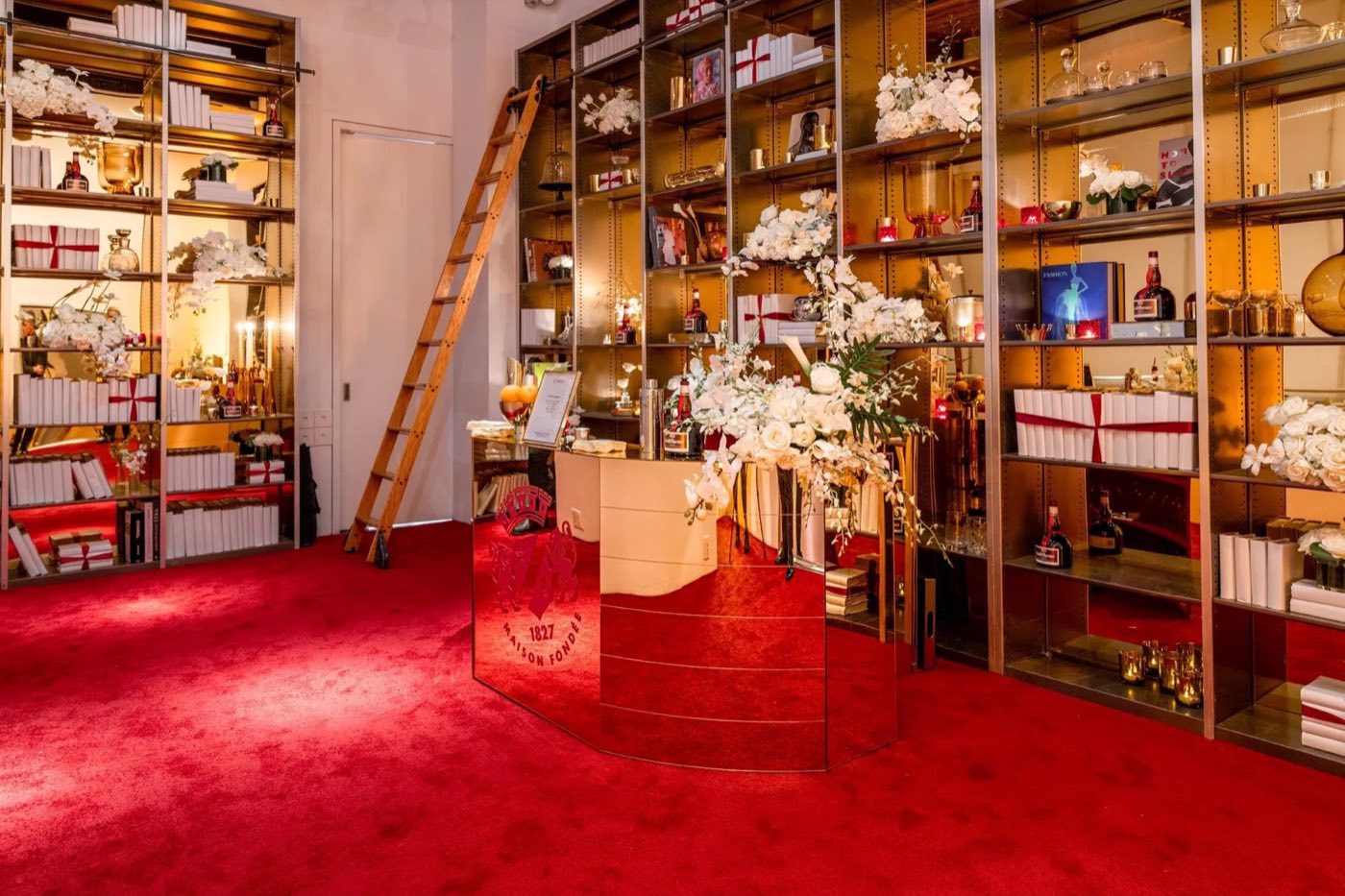 Studio built out as a retail pop-up with red carpet, shelving and a central counter