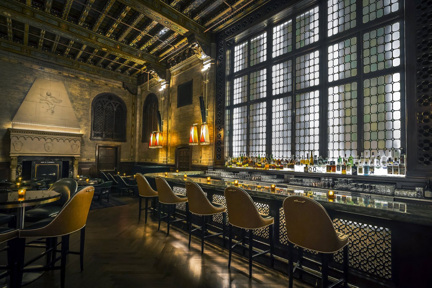 Long quartzite bar beneath tall leaded windows and a painted wood ceiling