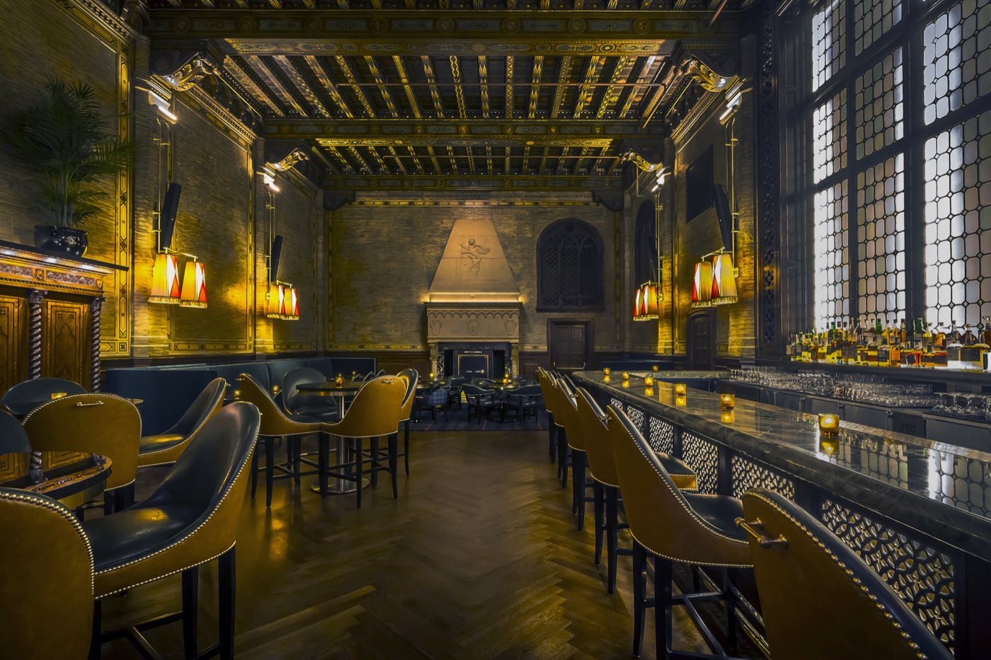 Main room looking toward the stone fireplace with bar stools and brass sconces