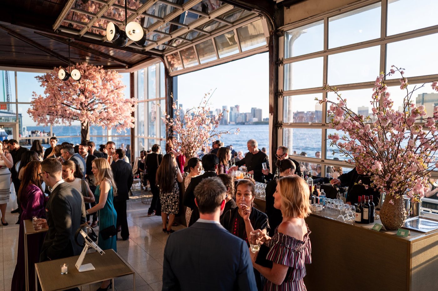 Guests mingle in the glass-walled main room with river doors open to the Hudson