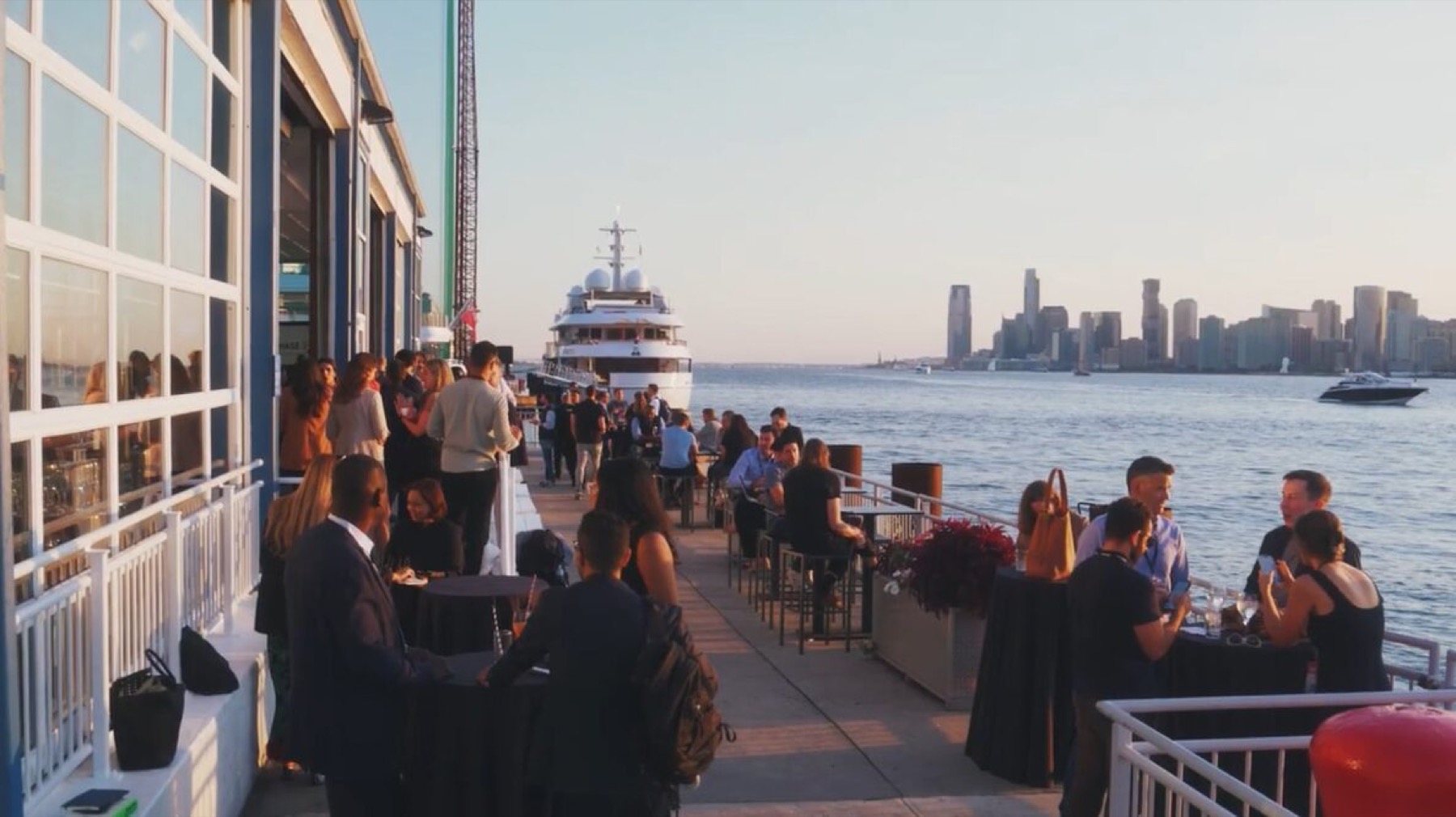 Guests at tables along the outdoor pier terrace with the Hudson River and skyline