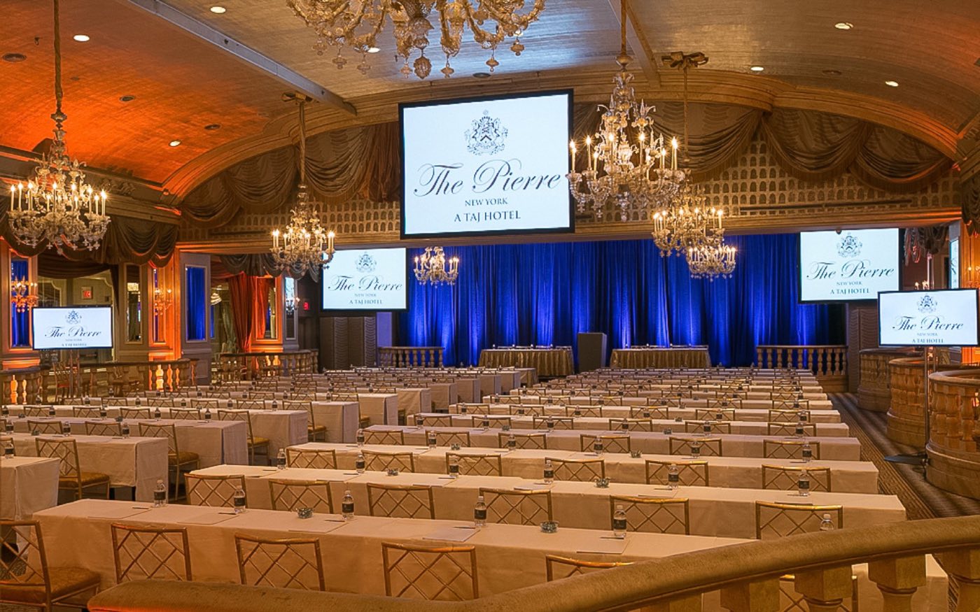 Ballroom set theater style with chandeliers, screens and a lectern