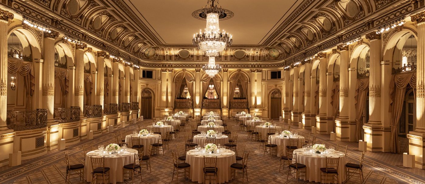 Grand Ballroom set with round dinner tables under crystal chandeliers and gilded arches