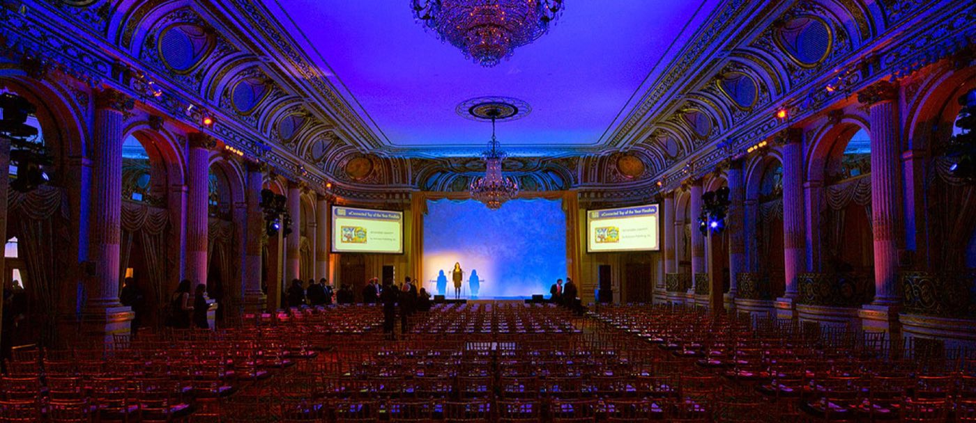 Grand Ballroom in theater seating facing a stage with screens and blue lighting