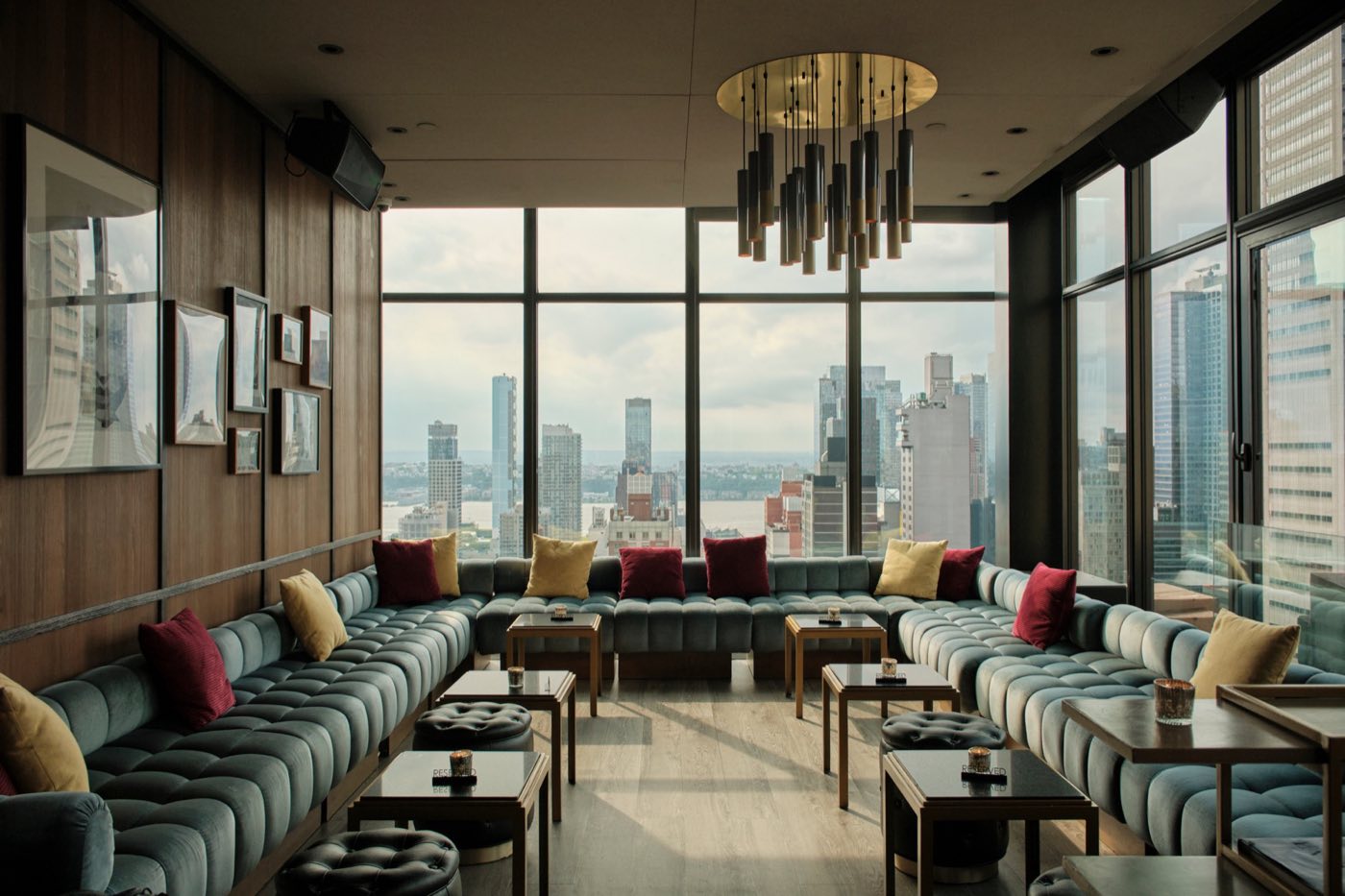 Main Lounge with tufted banquettes, low tables and corner windows facing the Hudson River