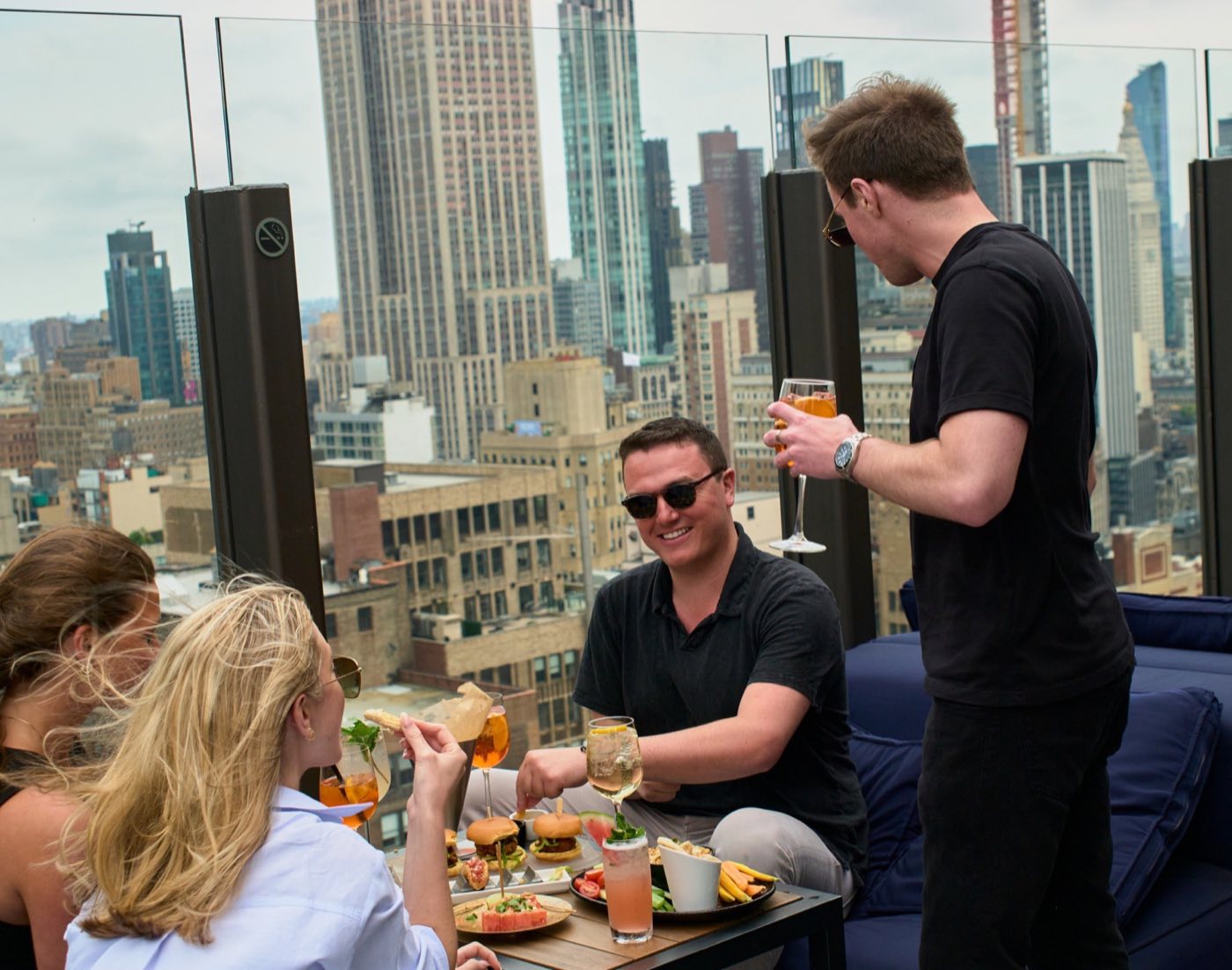Roof deck seating with glass railing and the Empire State Building behind