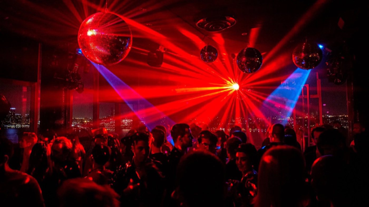 Top-floor club lit red with lasers and mirror balls over a crowded dance floor