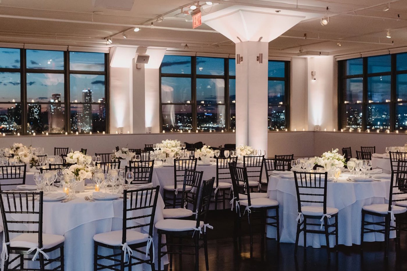 Tribeca 360 dinner setup with round tables and skyline views through tall windows