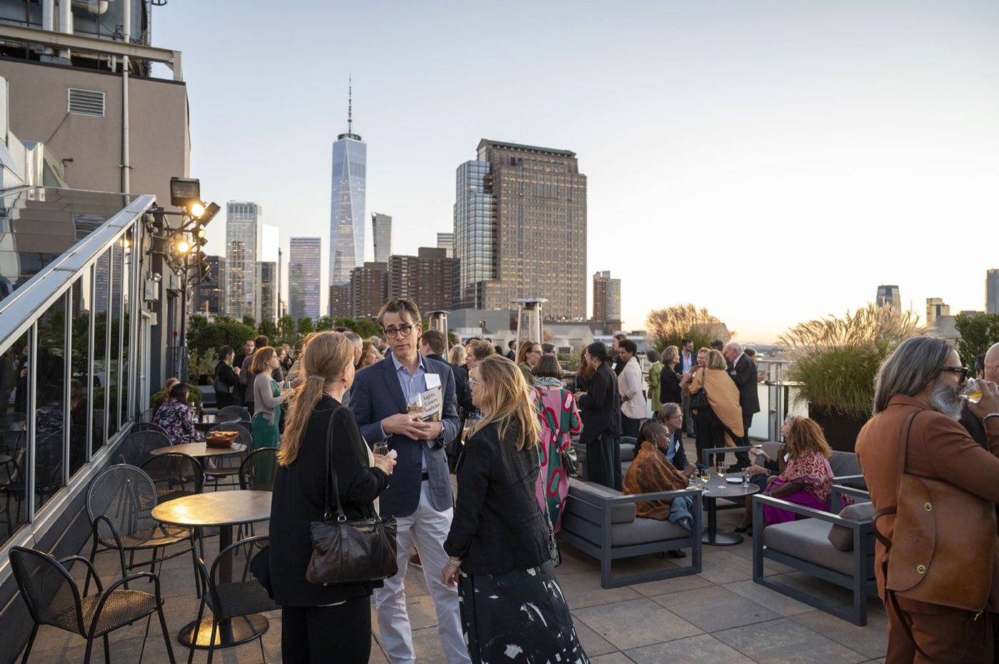 Guests mingling on the rooftop terrace with the downtown skyline behind