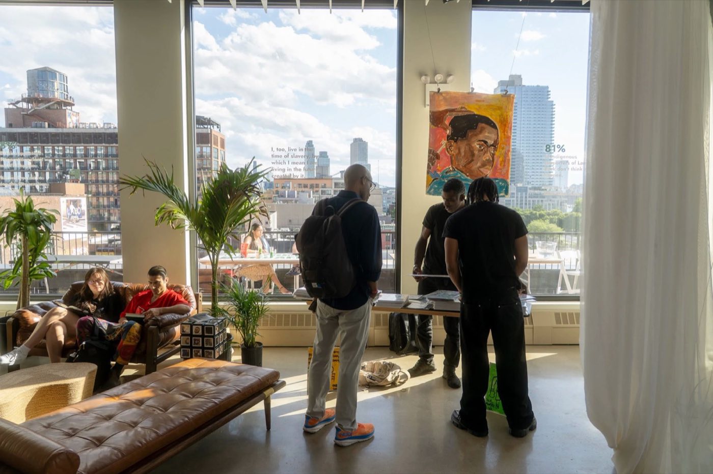 Sunny corner of the event floor with art on display, sofas and palms