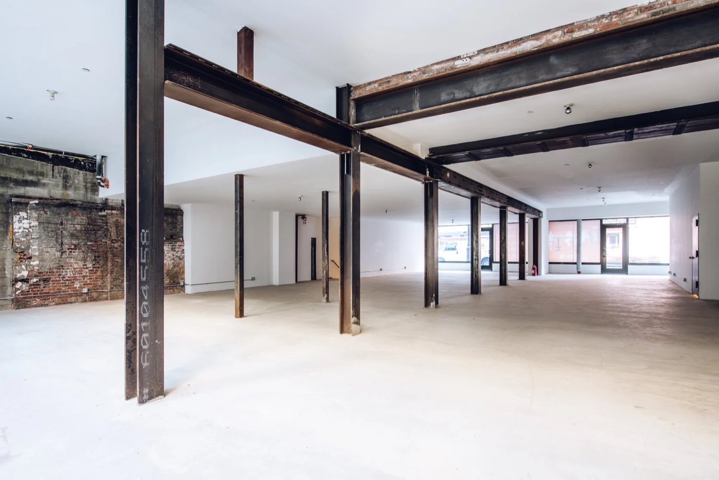 Long open floor with steel beams and columns leading to street facing windows