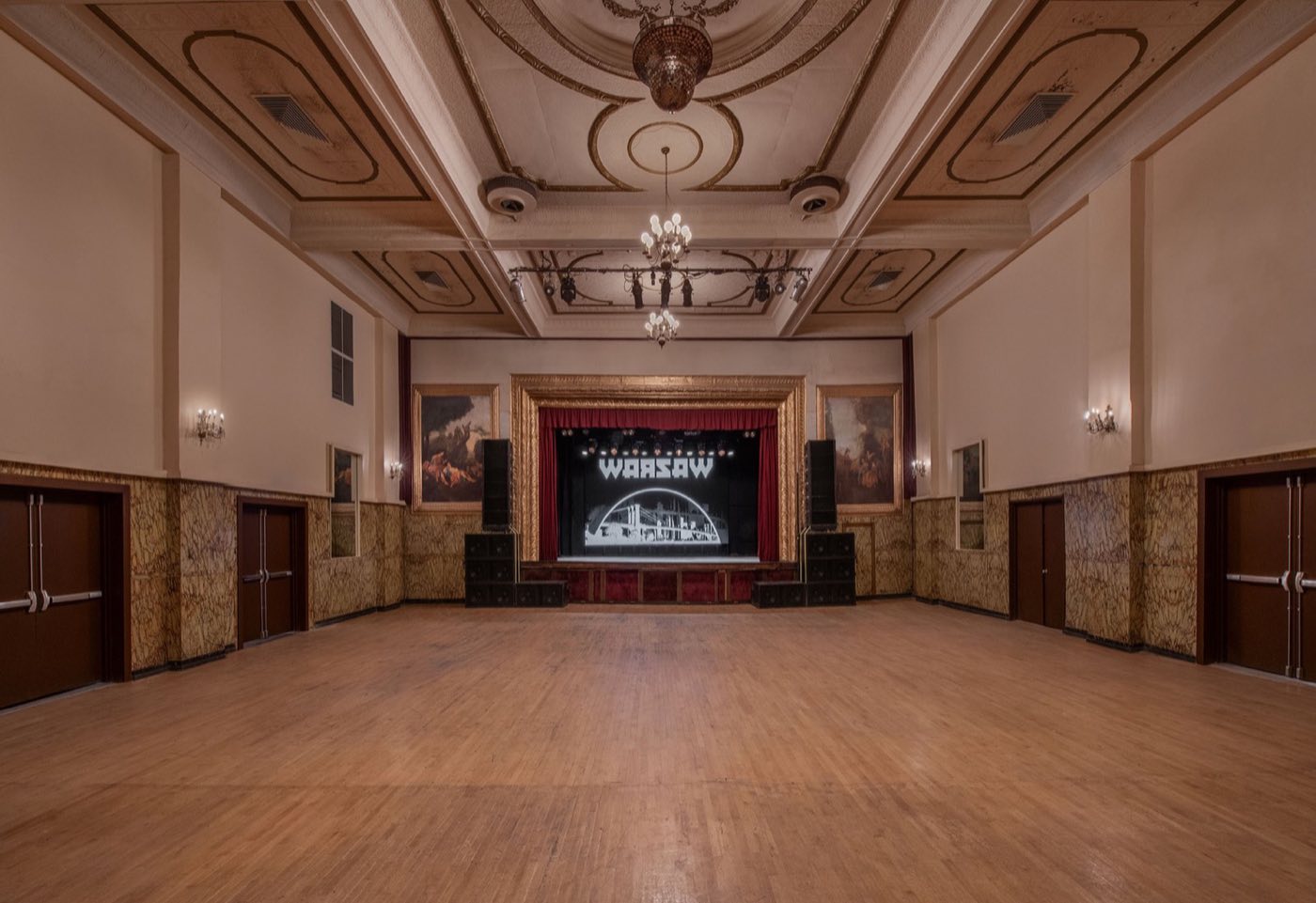 Empty music hall wood floor facing the stage under decorative ceiling medallions