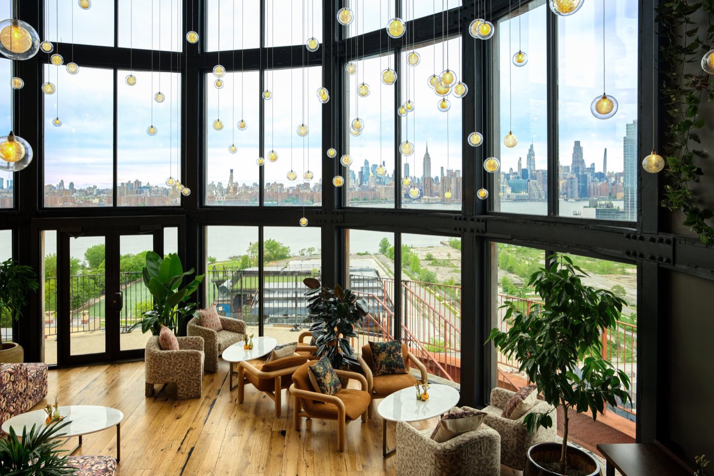 Round glass-walled water tower room with lounge seating and Manhattan skyline views