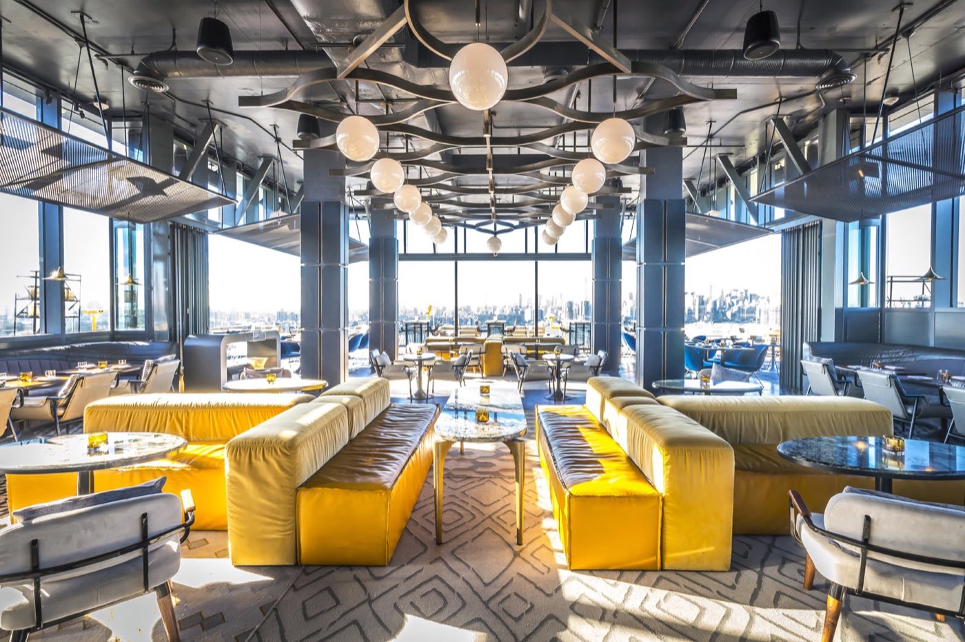 Westlight interior lounge with yellow banquettes, globe pendants and floor-to-ceiling windows