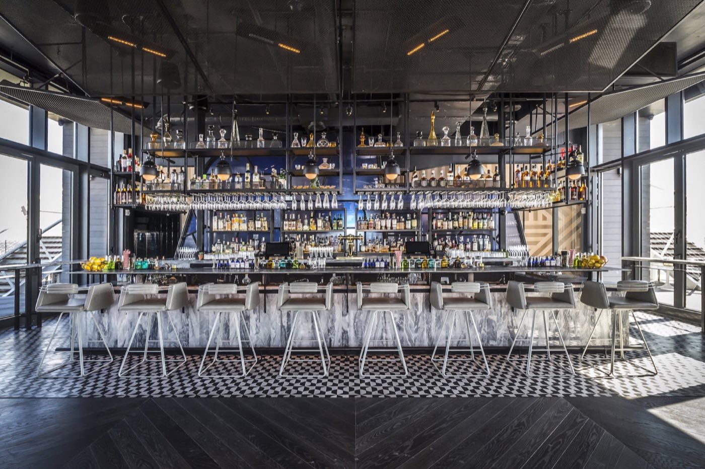 Center bar with backlit shelving and a row of stools under the rooftop ceiling