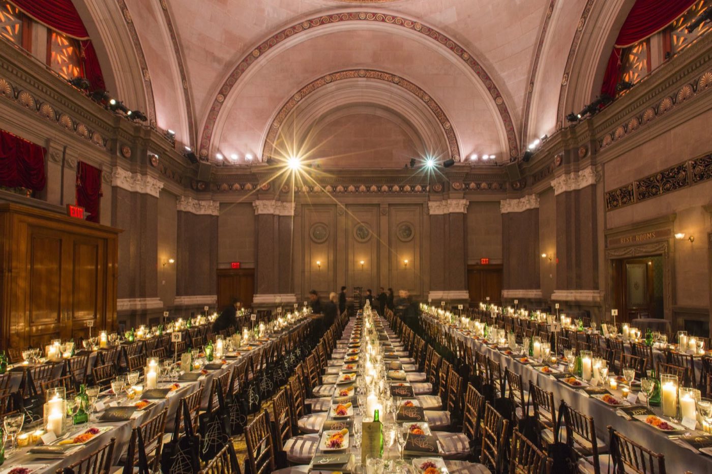 Long banquet tables set for dinner under the vaulted rotunda arches