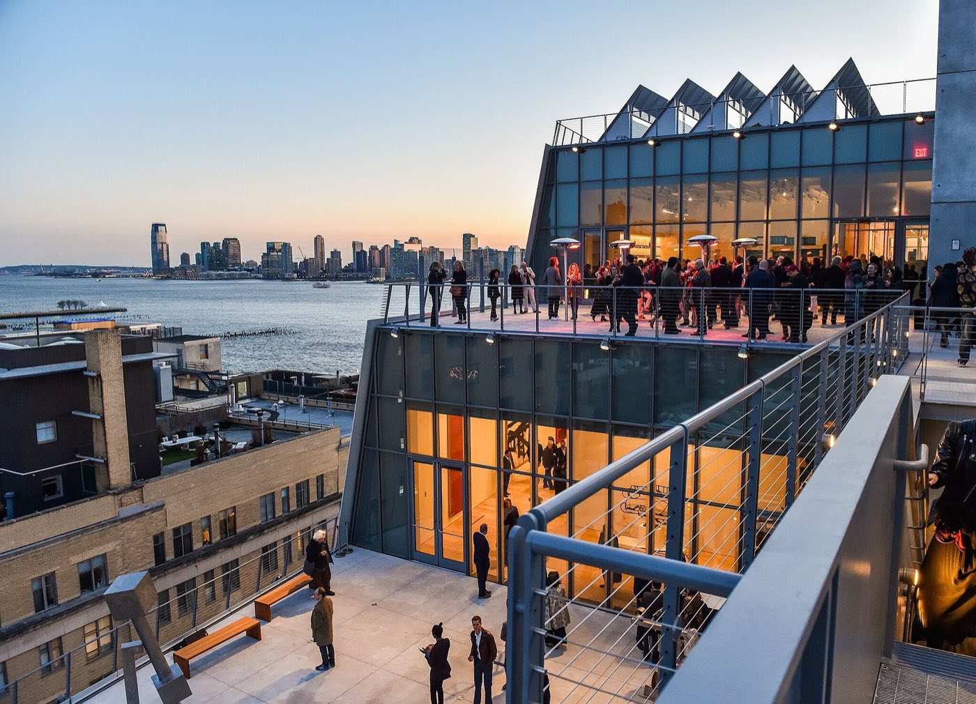 Eighth-floor terrace with a sawtooth skylight roof and river views at sunset
