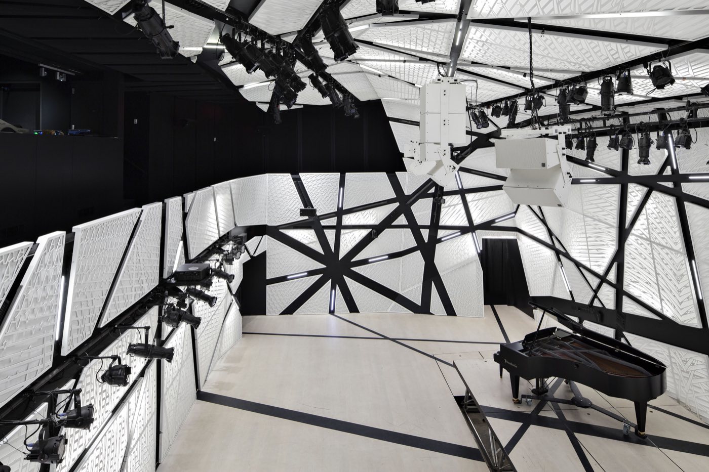 View from the balcony over an empty white hall with lighting rigs and a piano