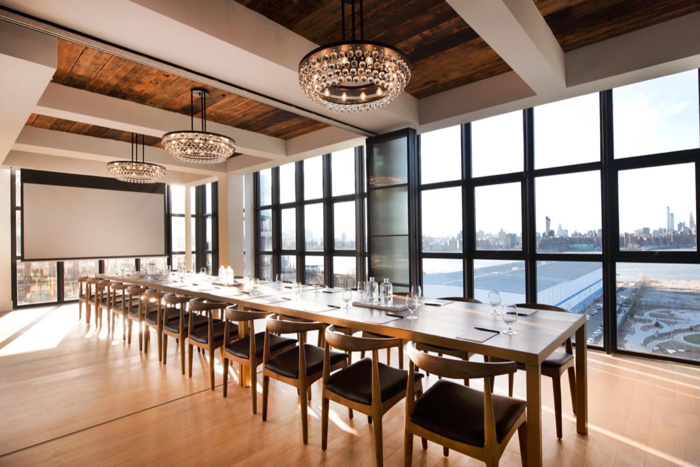 Penthouse loft with a long table beside tall windows facing the Manhattan skyline