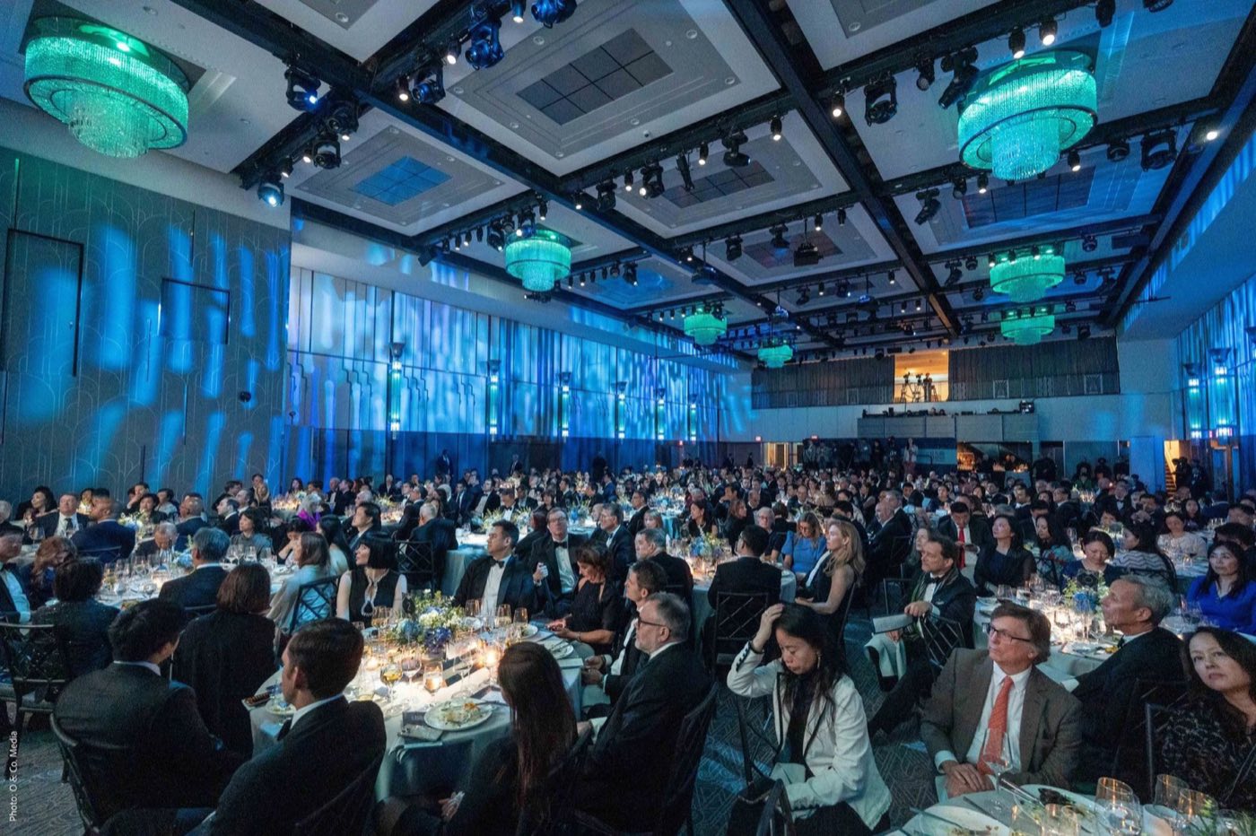 Seated gala dinner in the ballroom with guests facing a stage