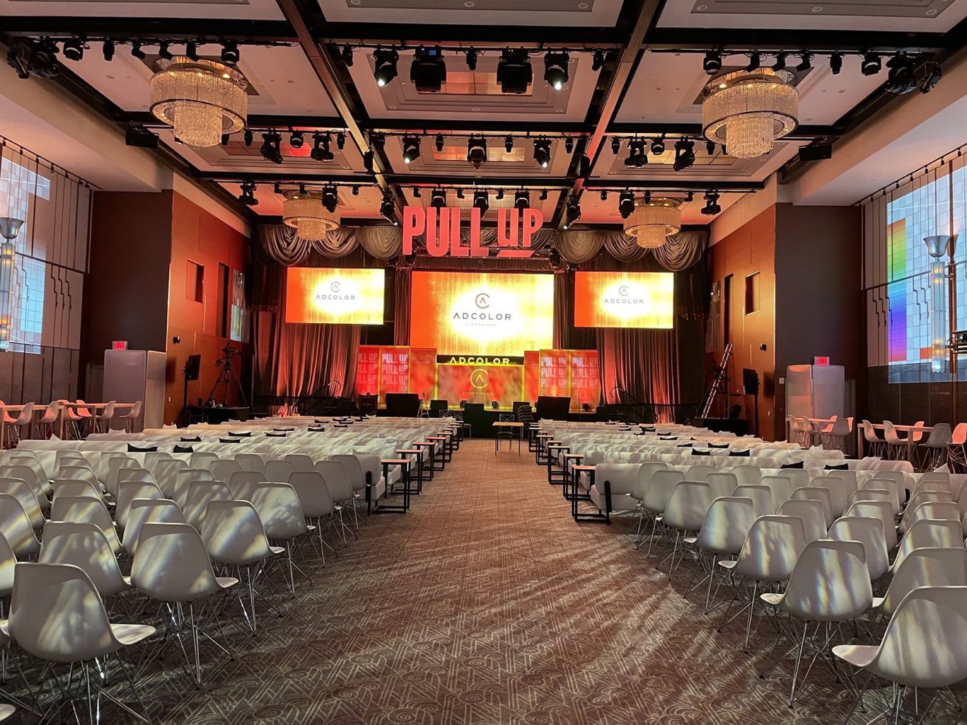 Theater-style rows of chairs facing a stage with screens